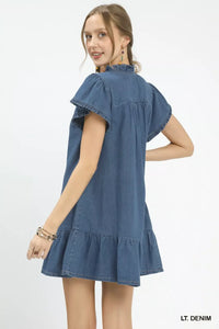 Woman wearing a light denim dress on a white background