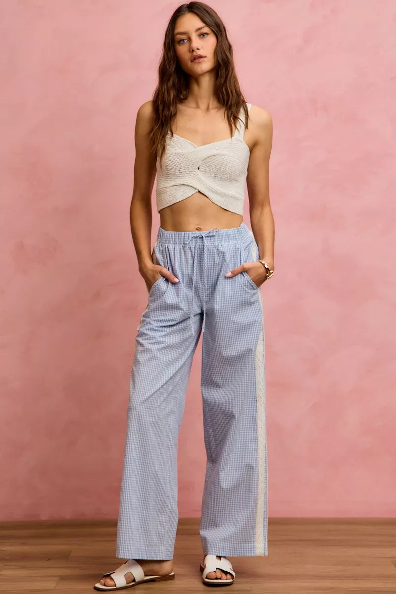 Woman wearing a white top and light blue checkered pants against a pink background