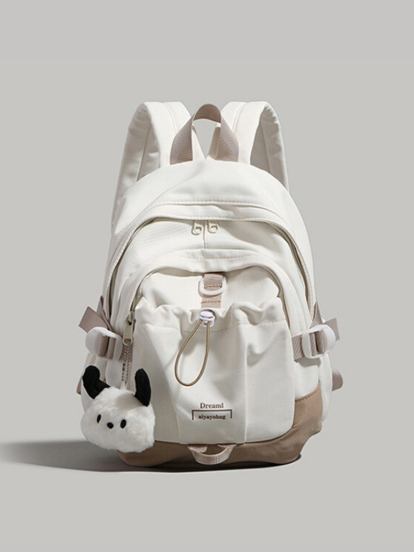 White backpack with plush toy attachment on a light gray background