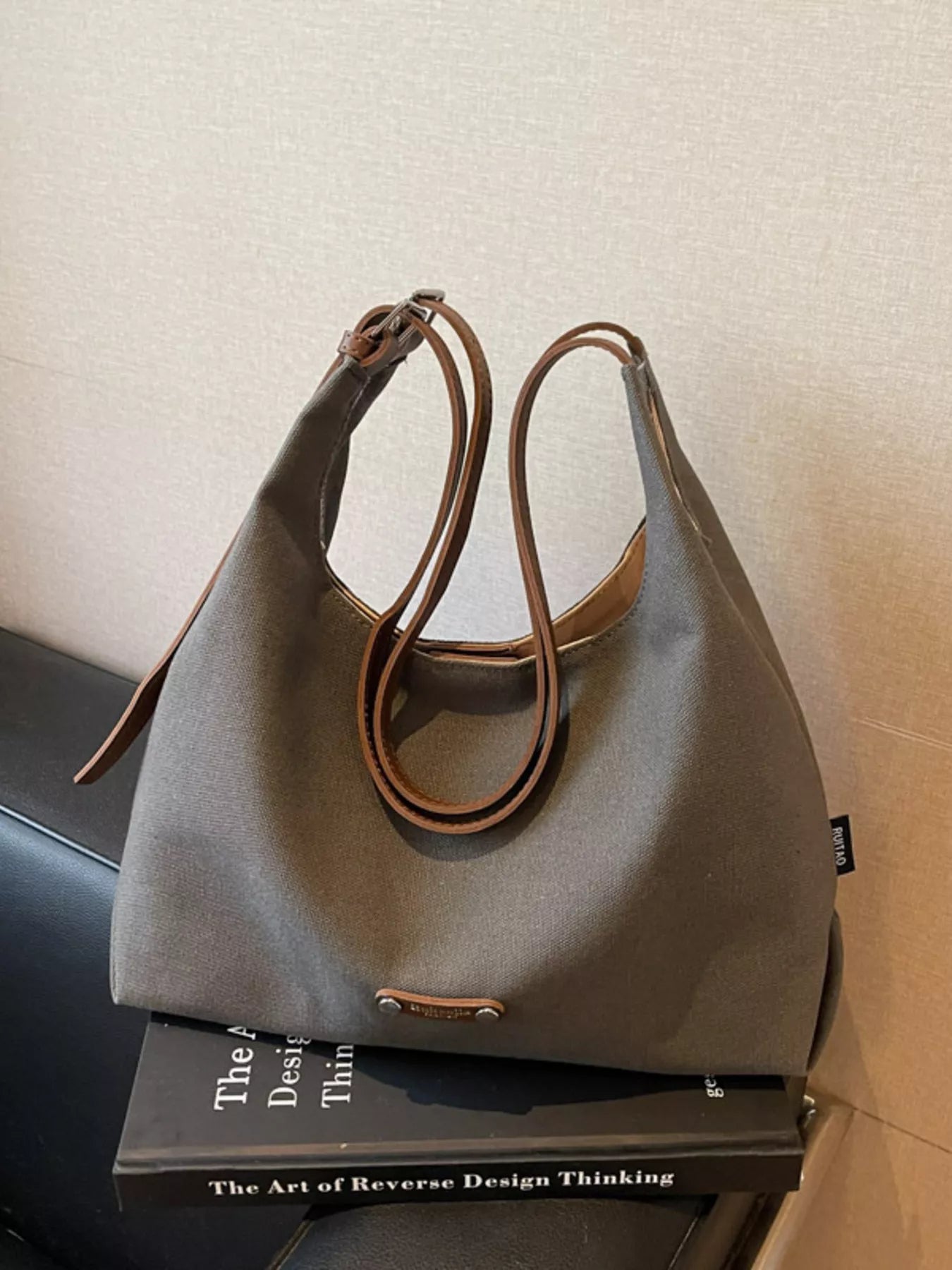 Gray handbag with brown handles on a black surface