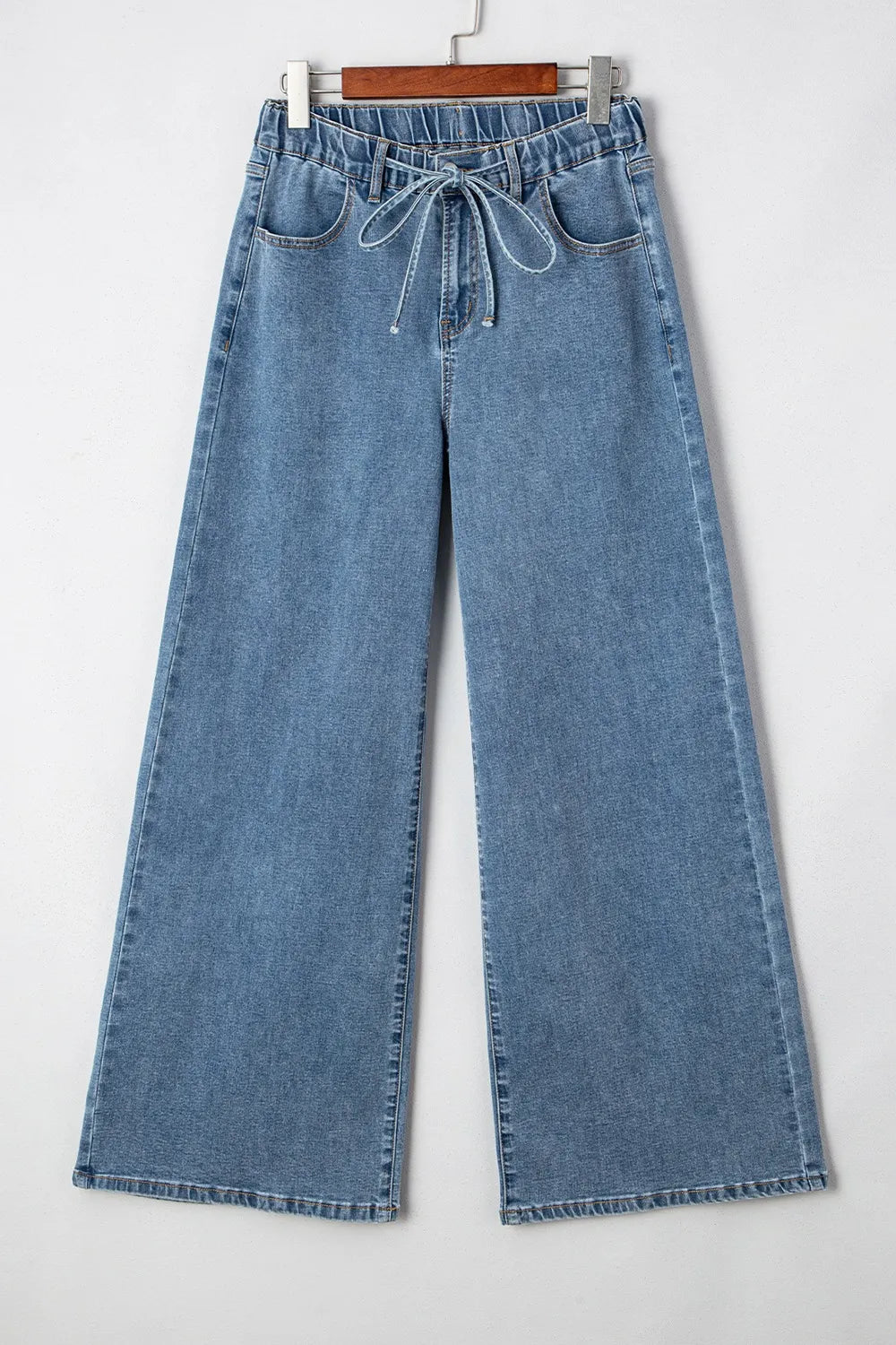 Blue jeans on a hanger against a white background