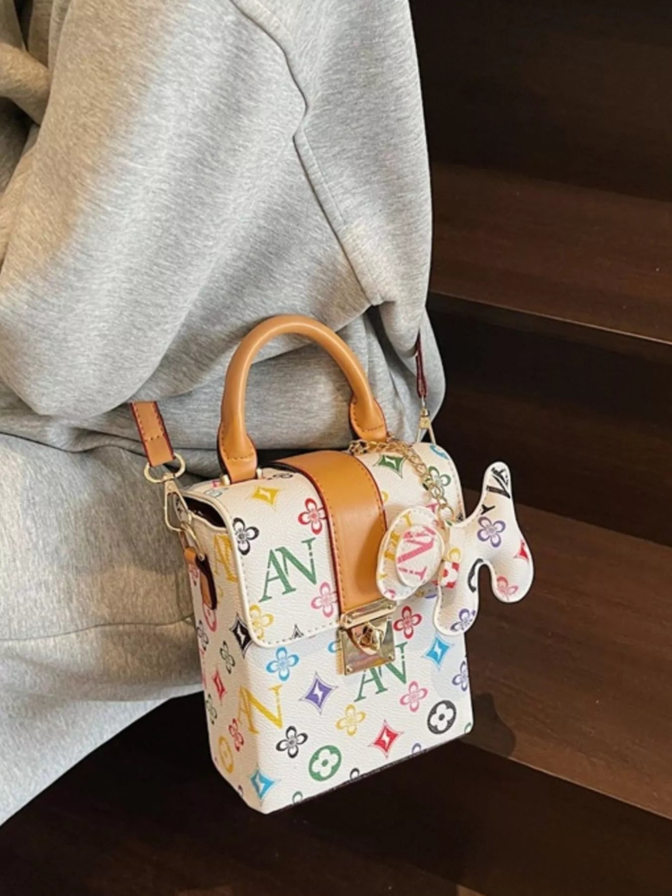 Small handbag with colorful logo pattern worn by a person
