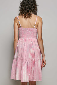 Woman wearing a pink checkered dress against a gray background