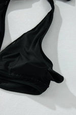 Black bikini top on a white textured surface