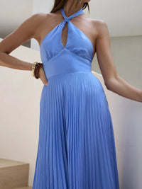 Woman wearing a blue pleated dress with a neutral background