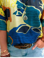 Person wearing a colorful shirt with abstract patterns and a necklace.