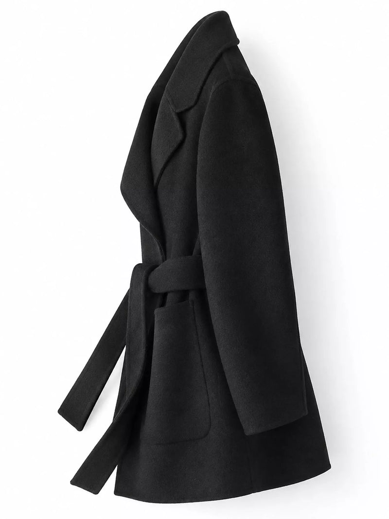 A black belted coat with wide lapels and front patch pockets, shown from a side profile view against a plain white background.