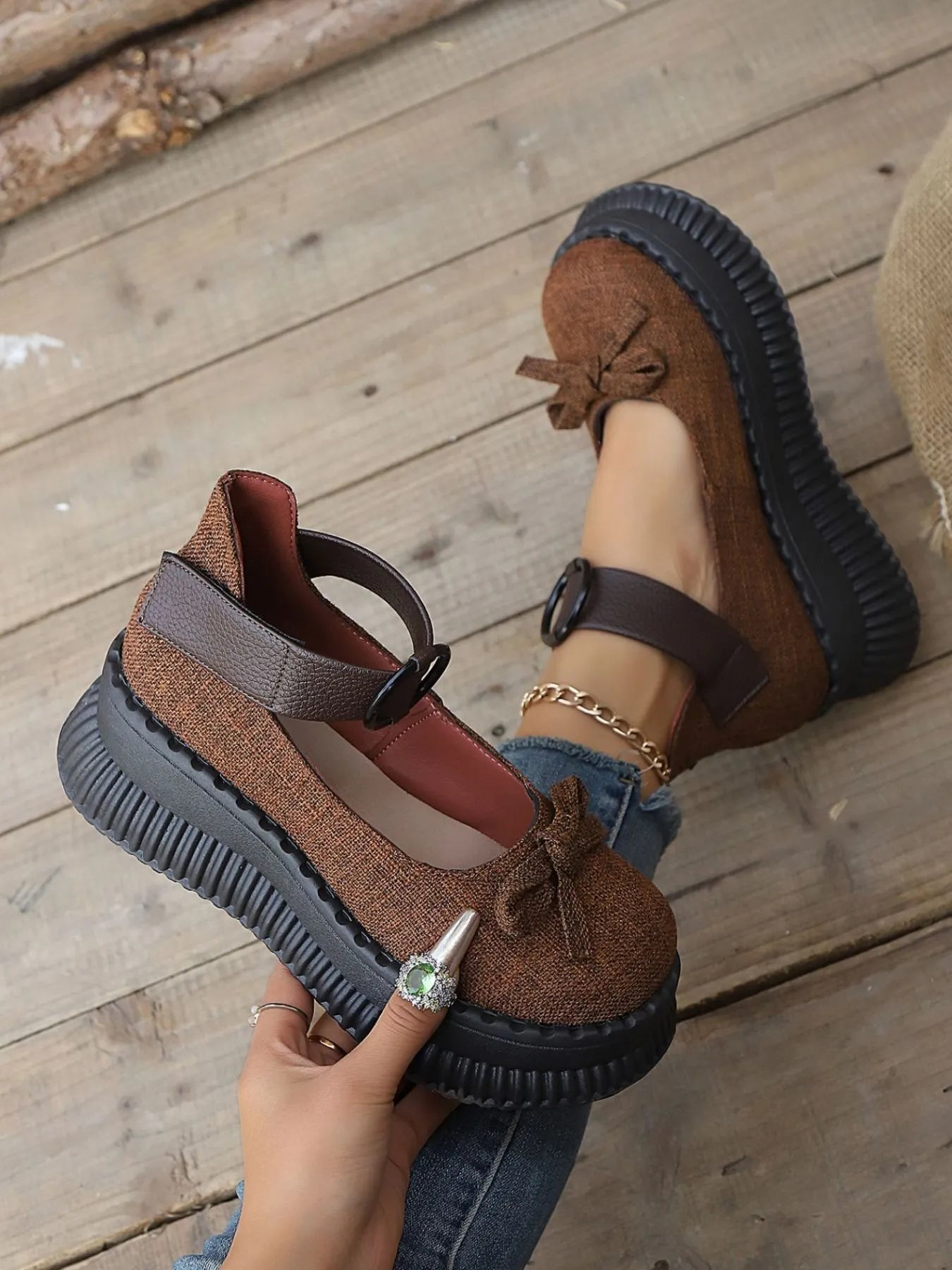 Brown suede shoes with black soles on a wooden floor