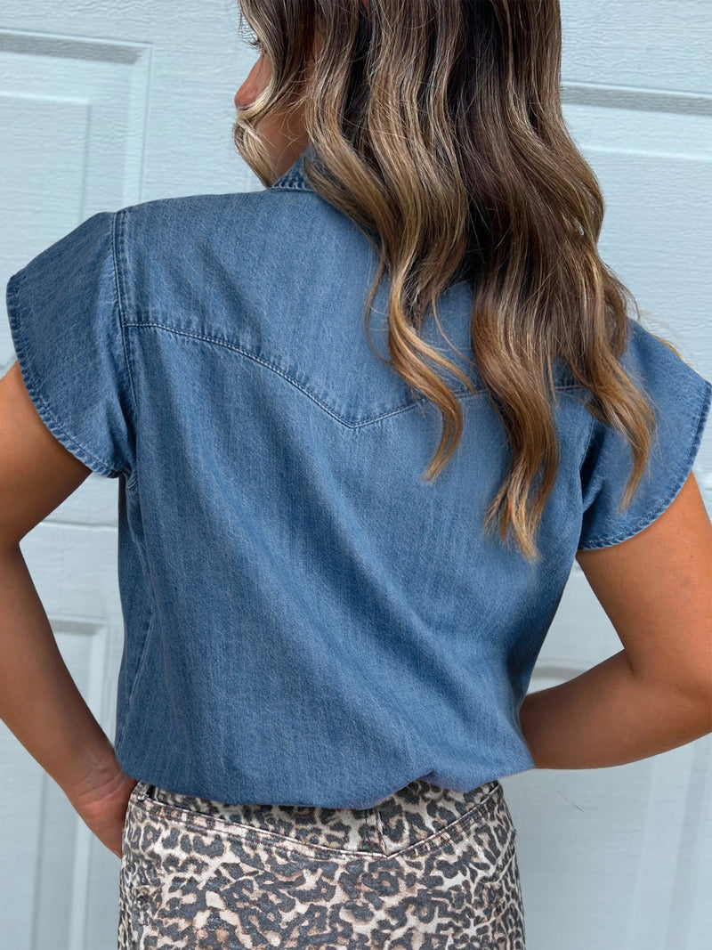 Person wearing a blue denim shirt with a white door background