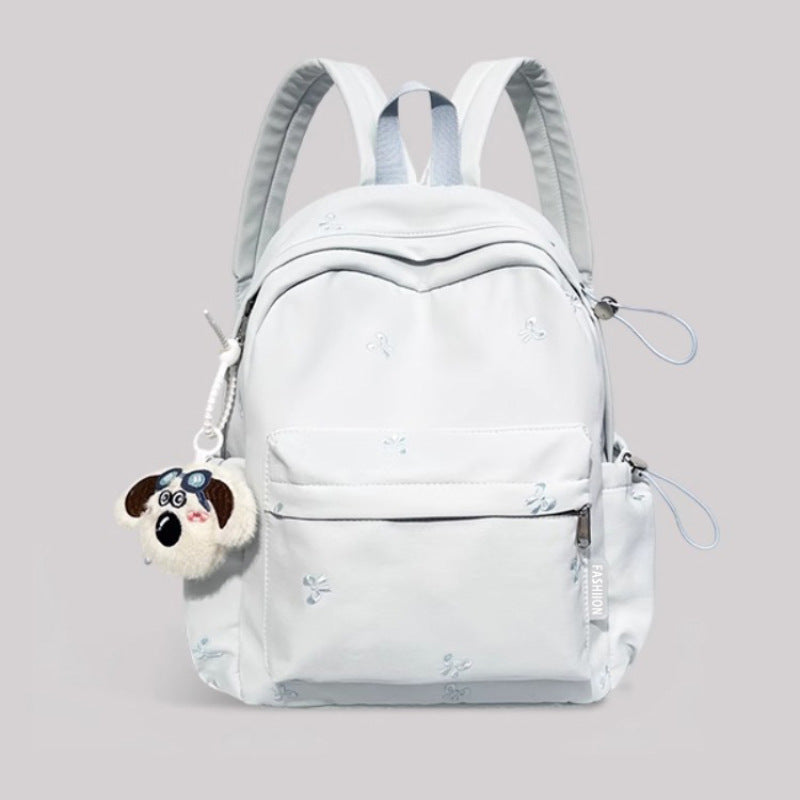 Light blue backpack with a dog-shaped charm on a gray background