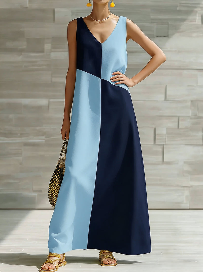 Woman wearing a blue and navy dress against a stone wall.