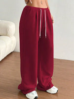 Maroon sweatpants with a white drawstring on a neutral background