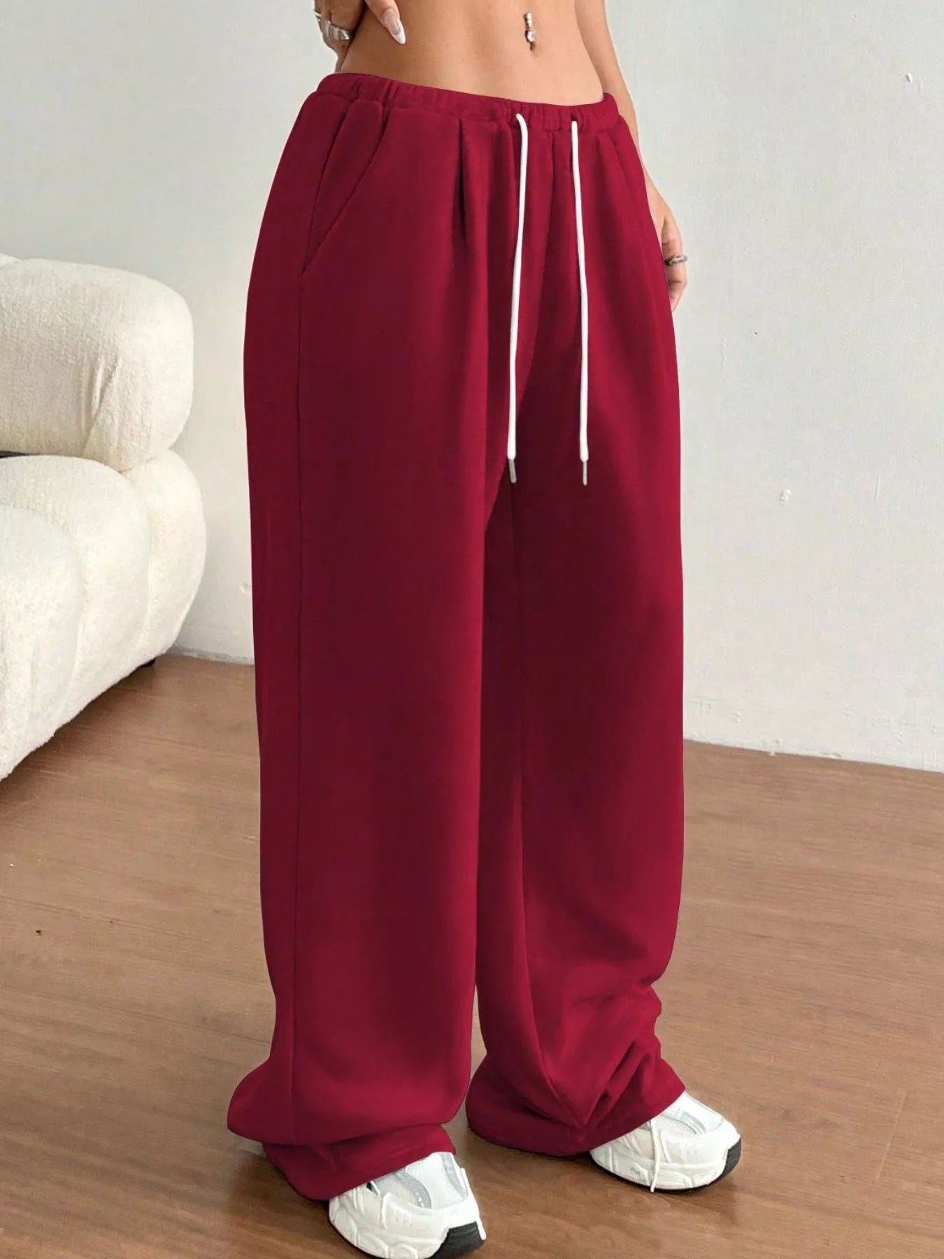 Maroon sweatpants with a white drawstring on a neutral background