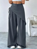 Person wearing gray wide-leg pants in a room with a white couch.