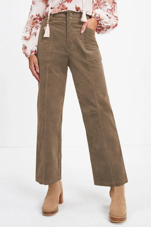 Person wearing brown corduroy pants with a floral blouse on a white background