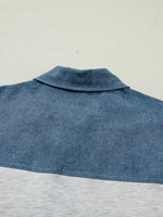 Close-up of a blue denim shirt collar on a light gray background