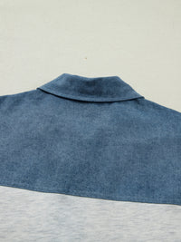 Close-up of a blue denim shirt collar on a light gray background