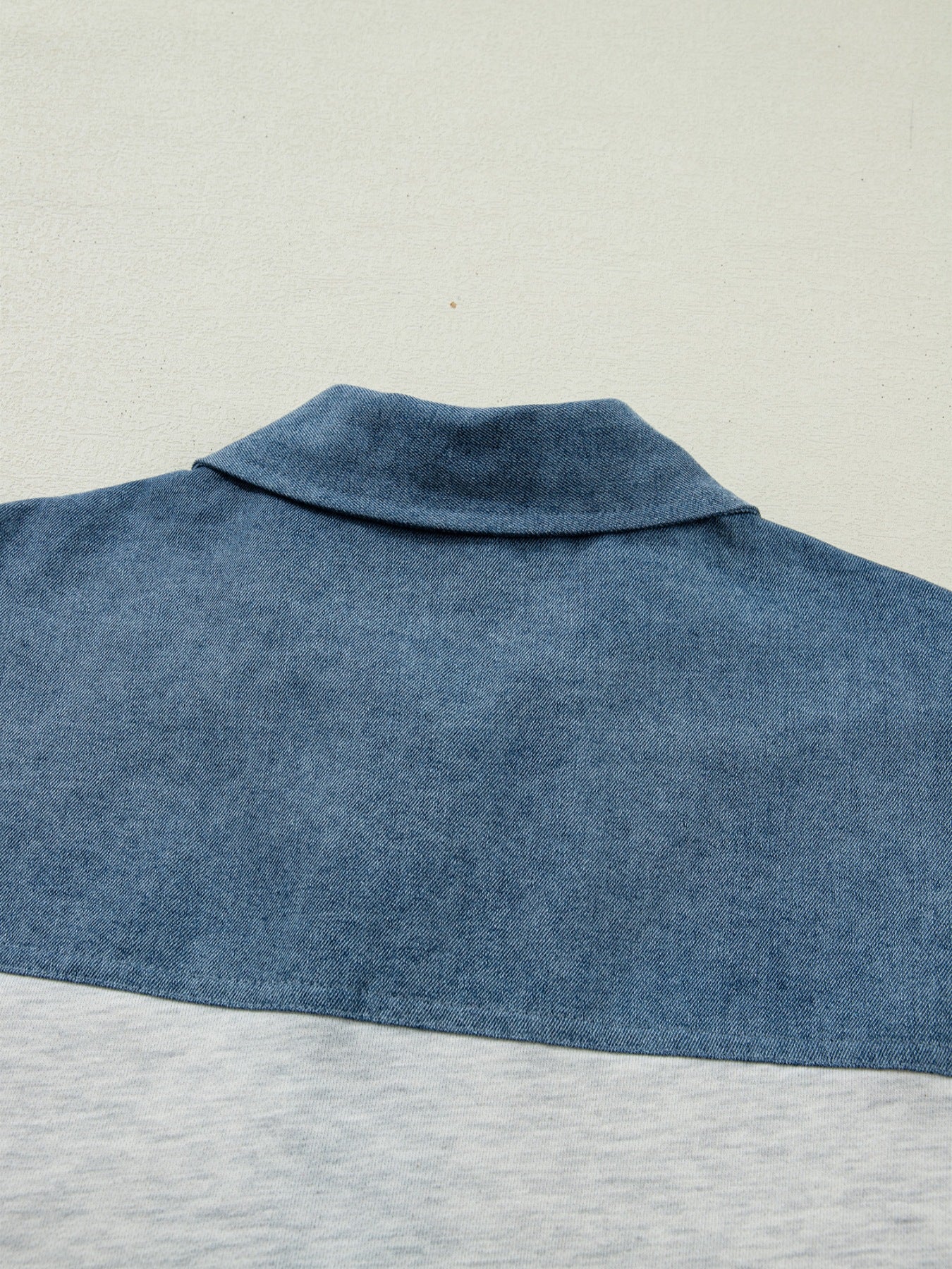 Close-up of a blue denim shirt collar on a light gray background
