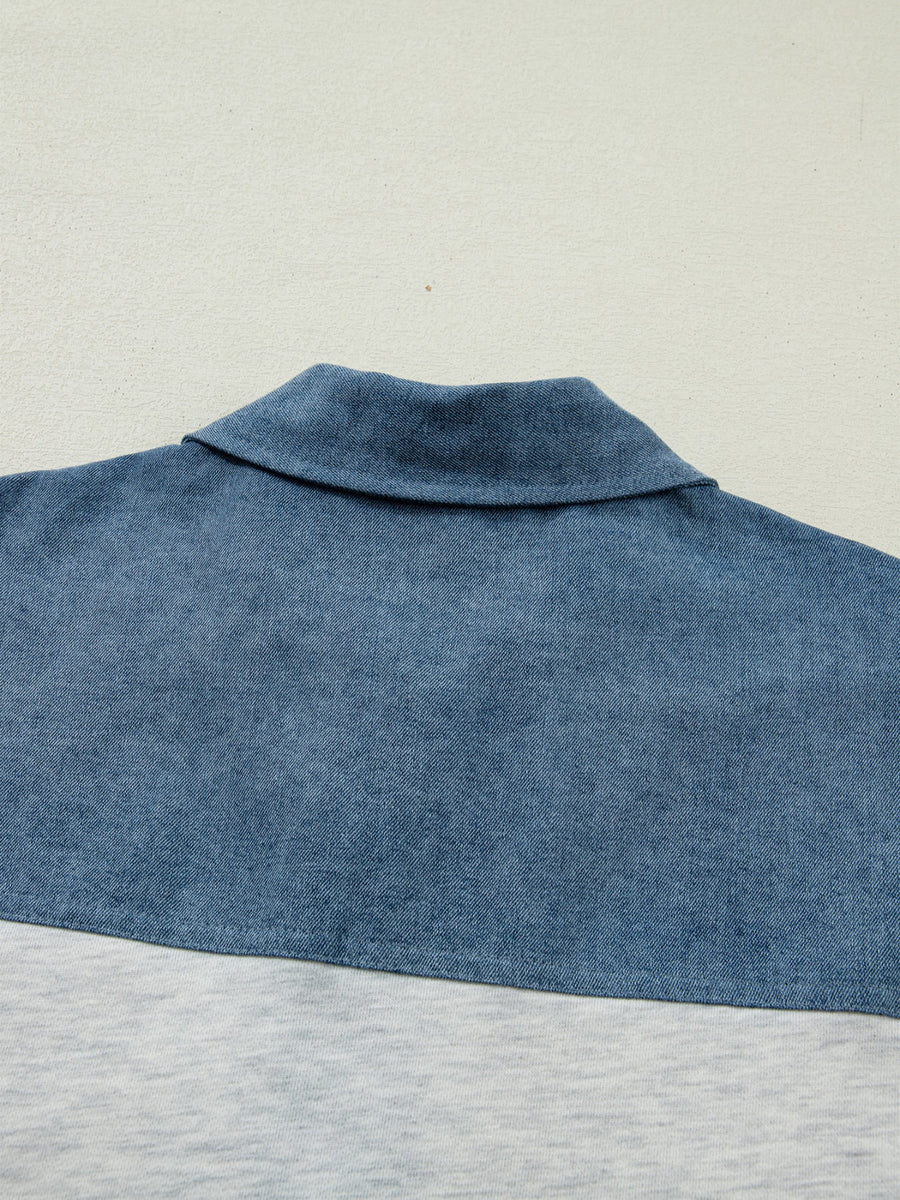 Close-up of a blue denim shirt collar on a light gray background