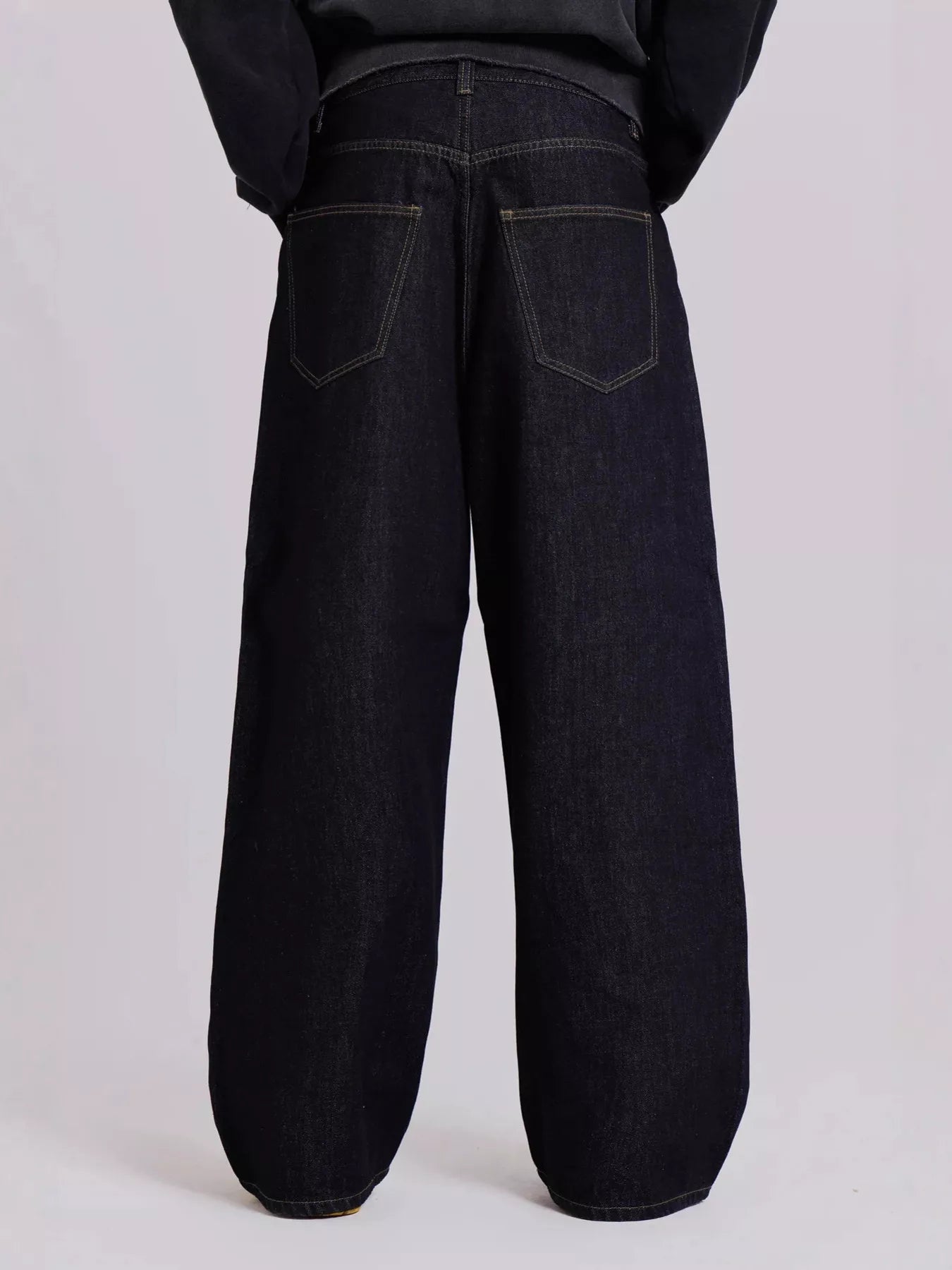 Black wide-leg jeans worn by a person on a light gray background