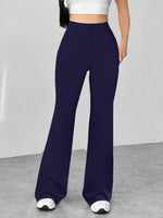 Navy blue flared pants worn by a person on a gray floor with a white wall background