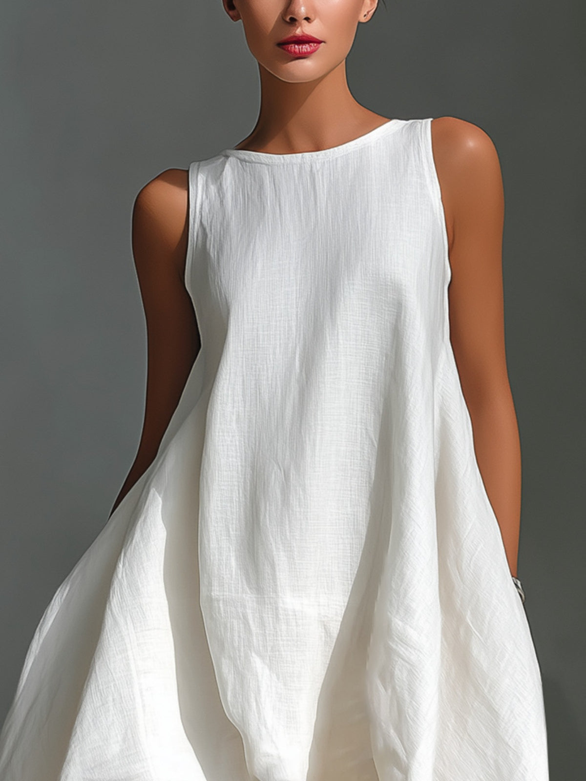 Woman wearing a white sleeveless dress against a gray background