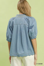 Light denim blouse worn by a person on a light green background