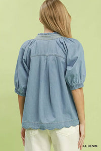 Light denim blouse worn by a person on a light green background