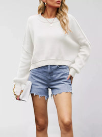 Woman wearing a white sweatshirt and denim shorts on a plain background