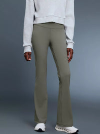 Person wearing olive green pants and a light gray sweater on a gray background