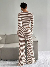 Person wearing a striped jumpsuit standing in a room with a gray couch and white floor.