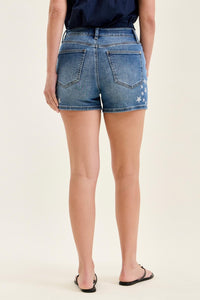 Person wearing blue denim shorts on a beige background