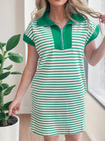 Woman wearing a green and white striped dress with a zipper detail indoors.