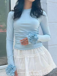 Light blue long-sleeve top with floral details and a white skirt.