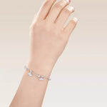 Silver bracelet with heart charms on a hand against a light background