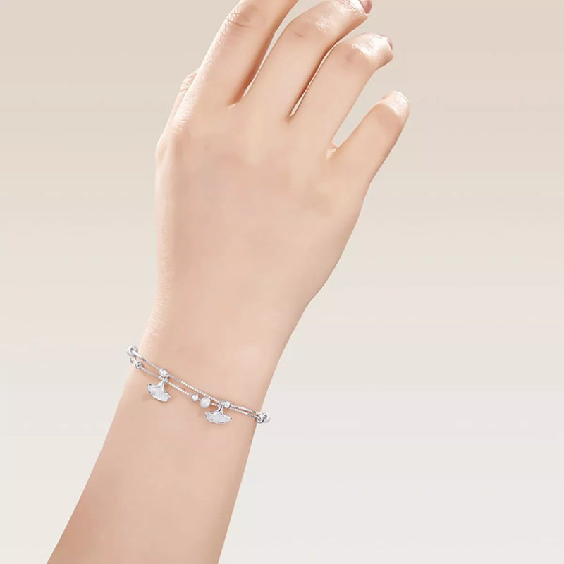 Silver bracelet with heart charms on a hand against a light background