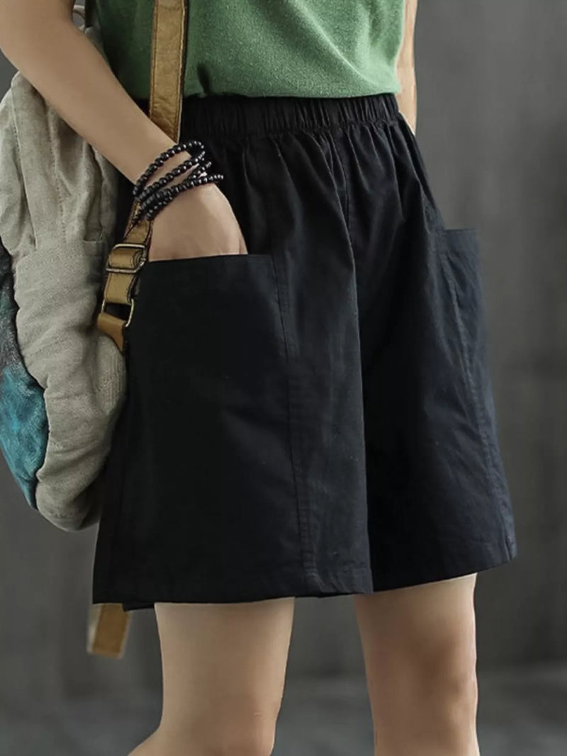 Person wearing a green top and black skirt holding a backpack against a gray background