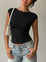 Person wearing a black top and light blue jeans with a beige handbag on a neutral background