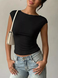Person wearing a black top and light blue jeans with a beige handbag on a neutral background