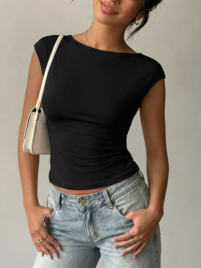 Person wearing a black top and light blue jeans with a beige handbag on a neutral background