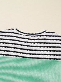 Close-up of a striped garment with black and white horizontal stripes on a beige background
