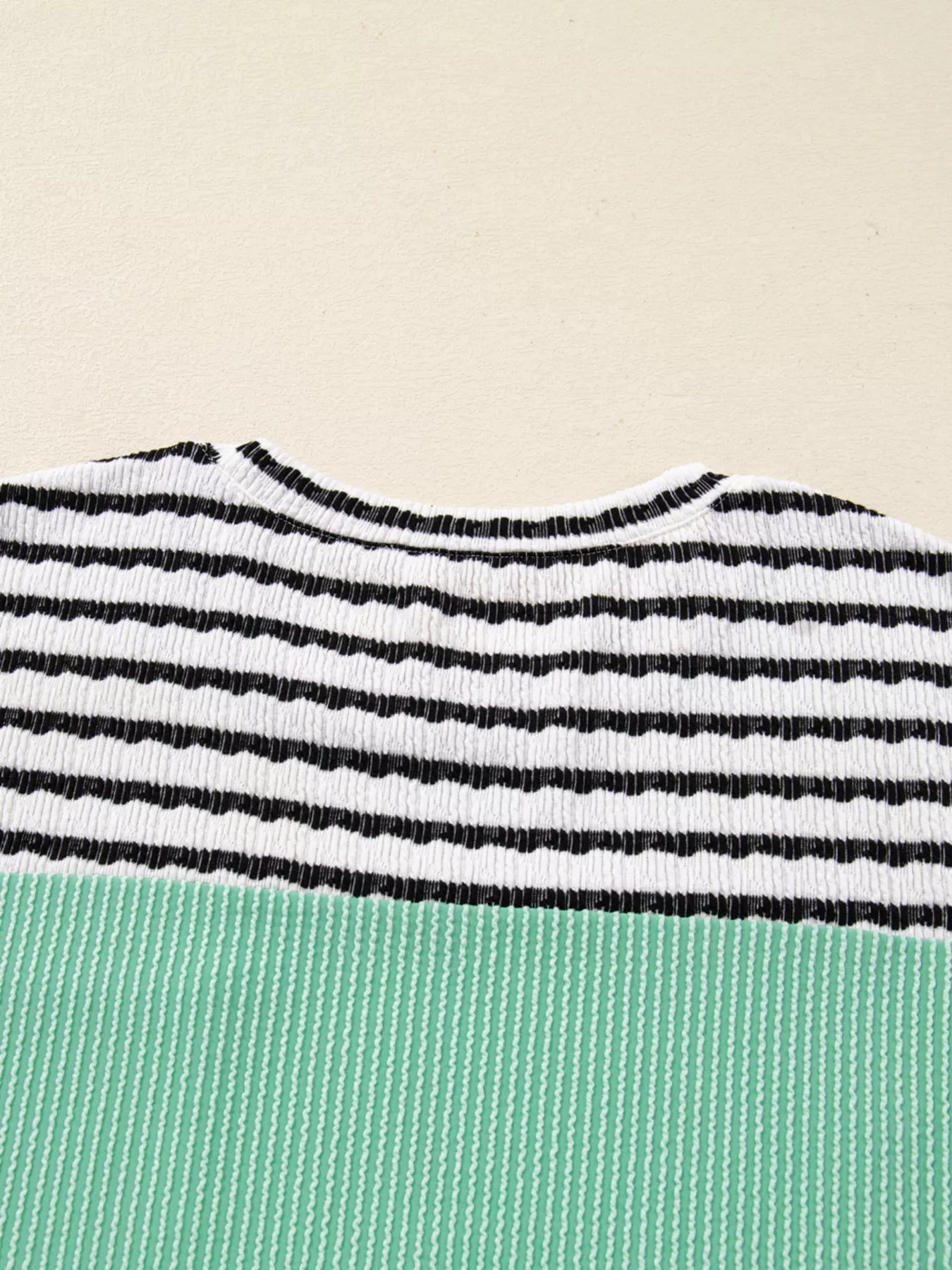 Close-up of a striped garment with black and white horizontal stripes on a beige background