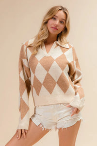 Woman wearing a diamond patterned sweater and denim shorts on a beige background