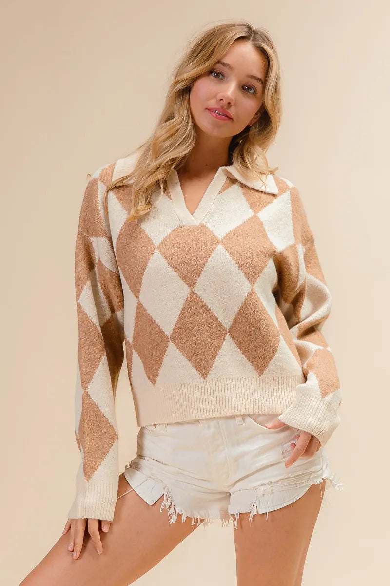 Woman wearing a diamond patterned sweater and denim shorts on a beige background