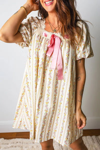 Woman wearing a floral dress with a pink bow in a home setting