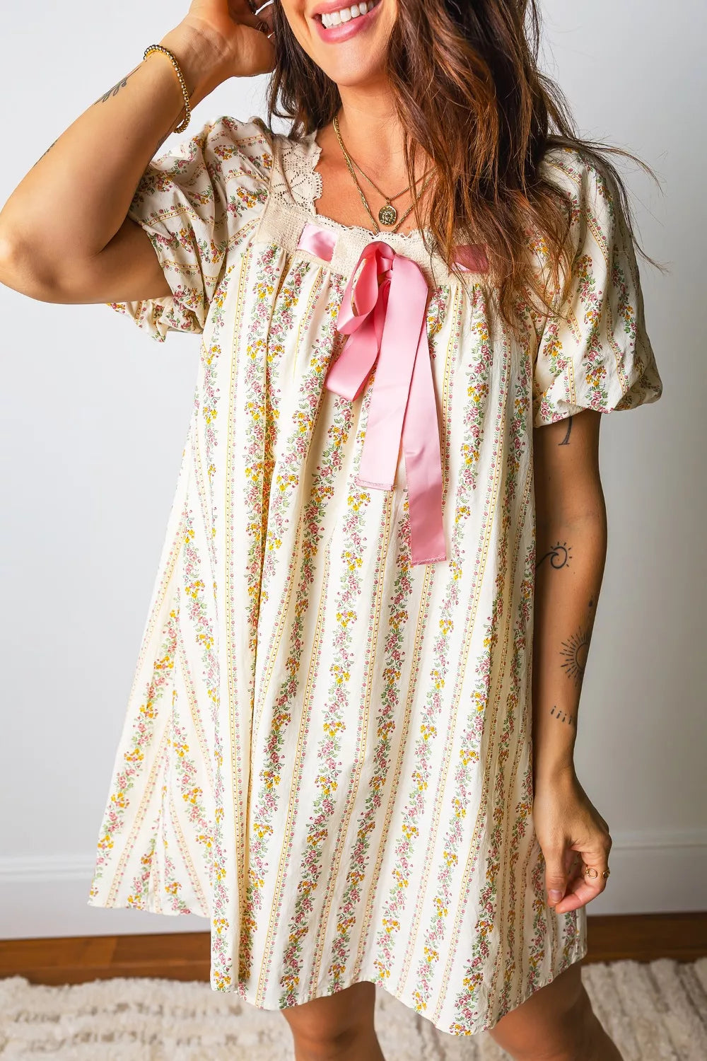Woman wearing a floral dress with a pink bow in a home setting