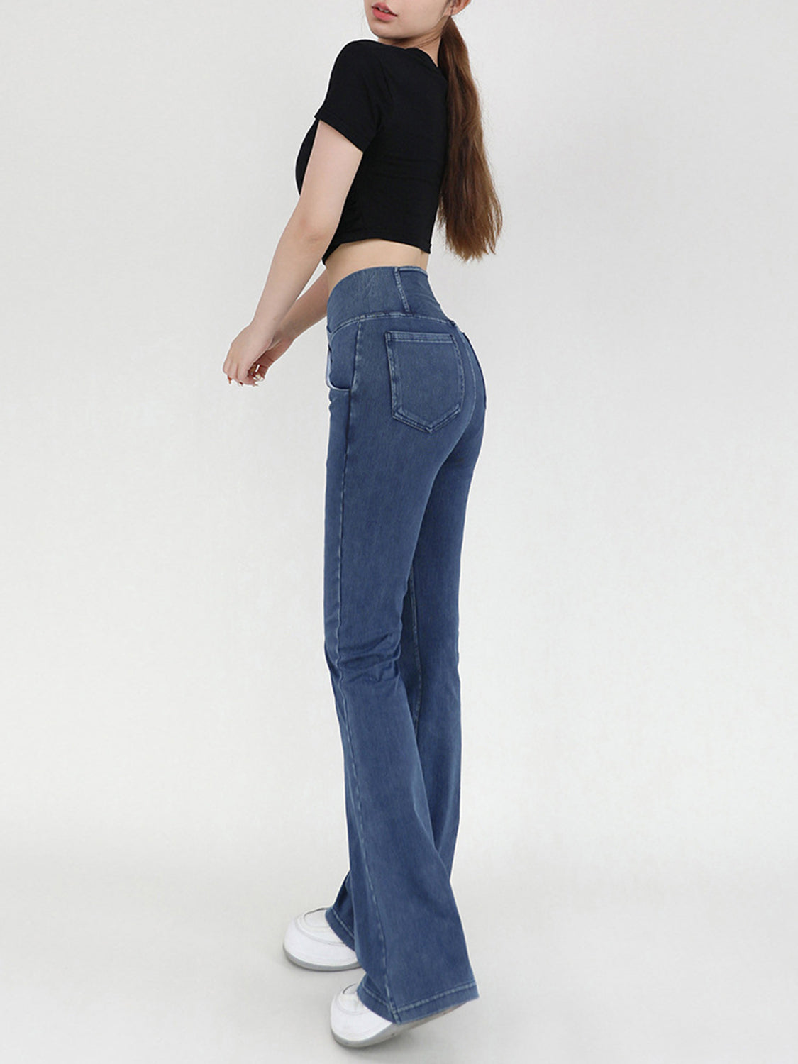 Person wearing blue jeans and a black top on a white background