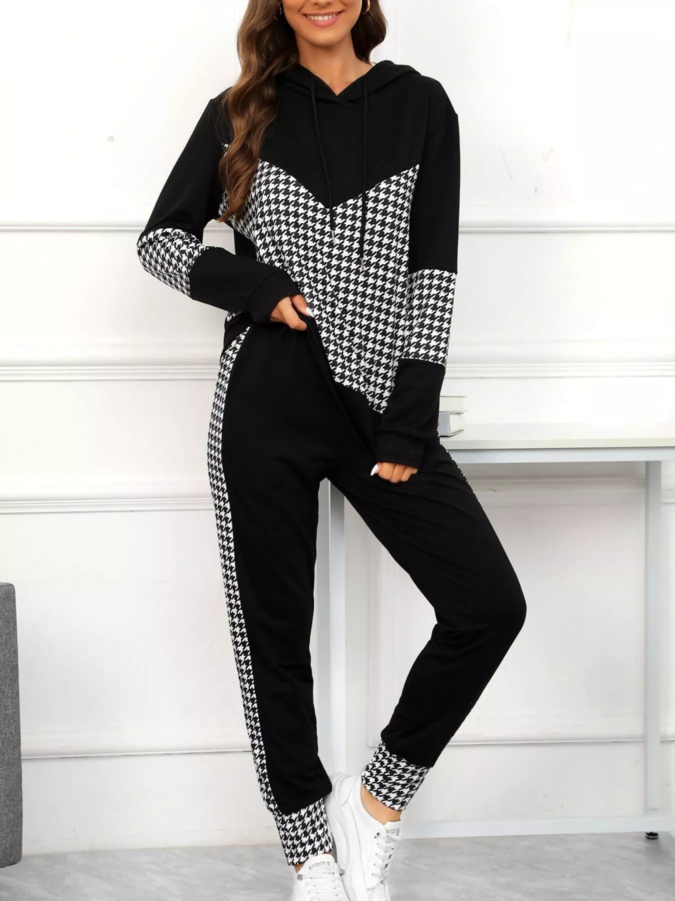 Woman wearing a black and white checkered hoodie and pants set on a white background