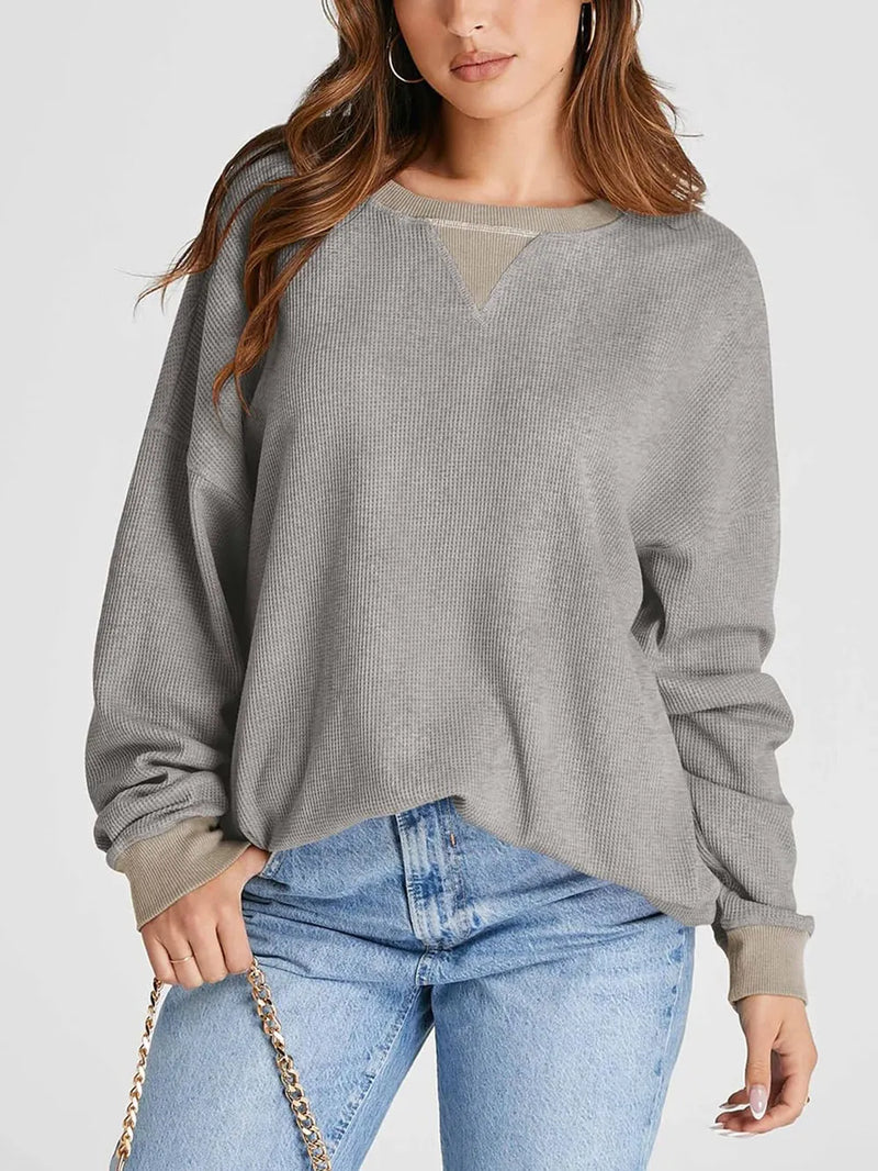 Woman wearing a gray sweater and blue jeans on a white background