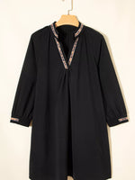 Black dress with lace trim on a hanger against a white background